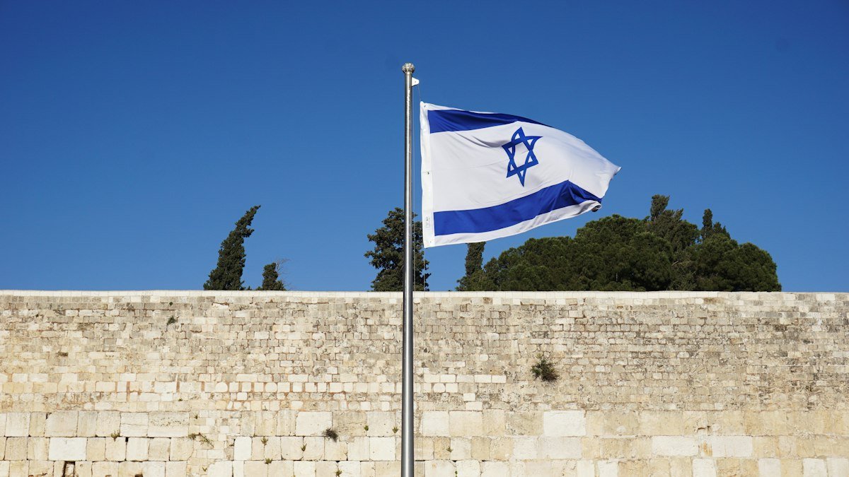 Israeli flag on a pole against the sky, a stock photo illustrating the Israel election