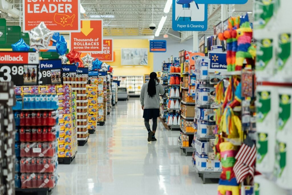 Shopper standing between supermarket shelves, representing rising grocery and cost-of-living prices in the US