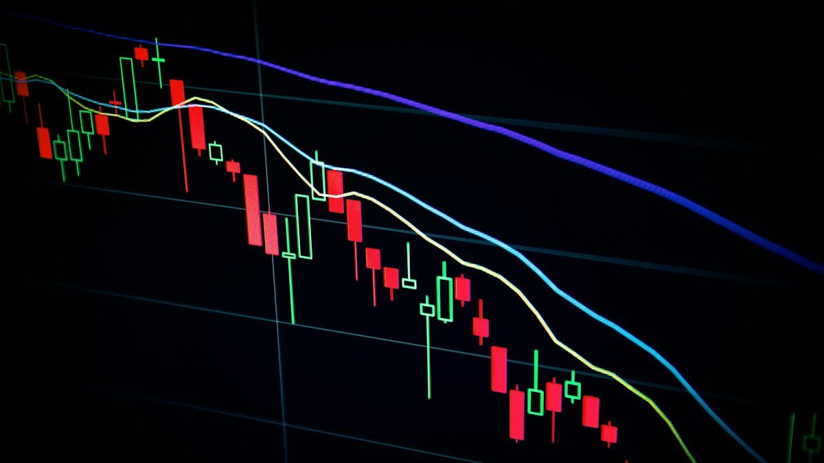 Stock market screens showing price charts, a stock photo illustrating Wall Street under pressure